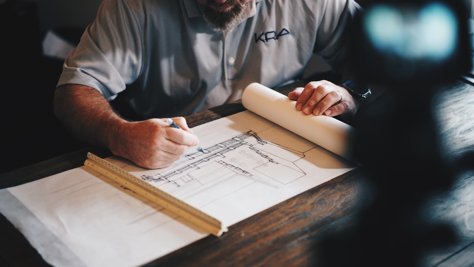 An architect drafting a technical drawing with pencil and ruler